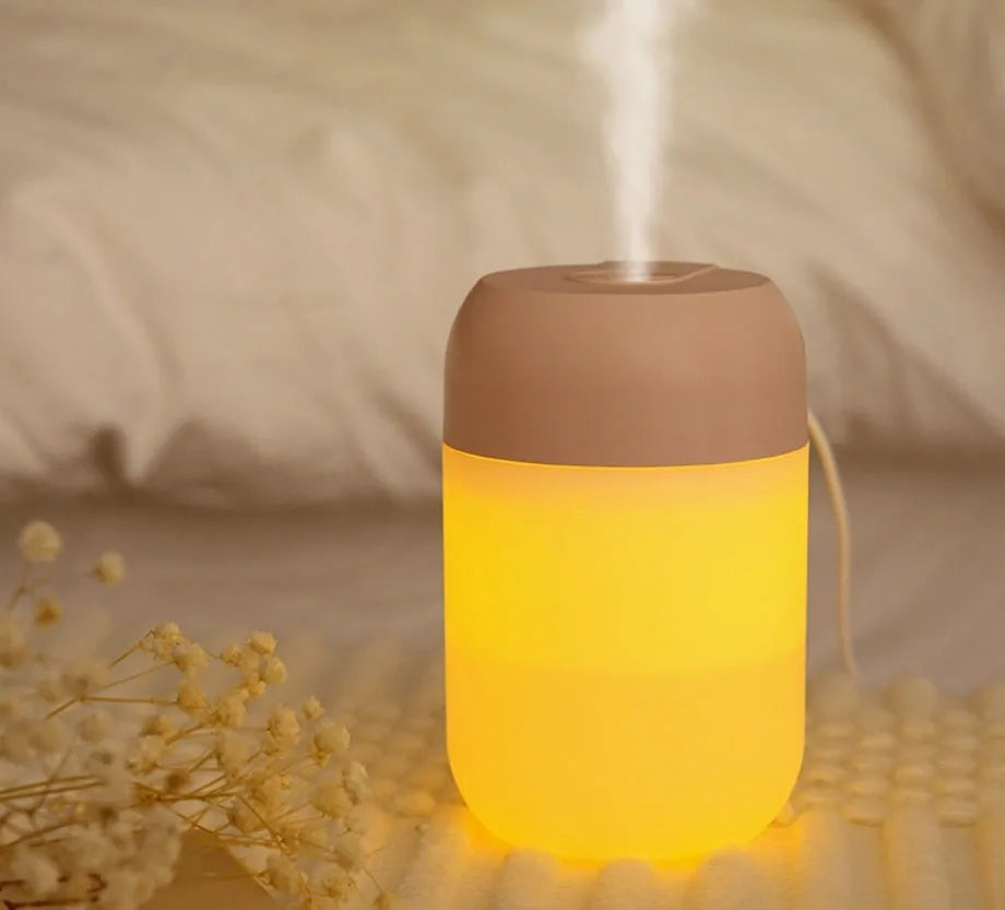 White cylindrical mini USB aromatherapy humidifier on a desk with charging cable.