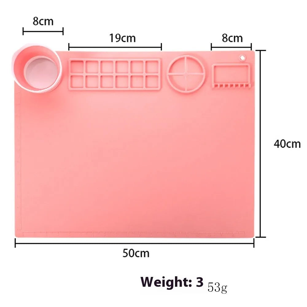 Light blue silicone painting mat with two round mixing bowls, placed on a wooden table with paintbrushes.