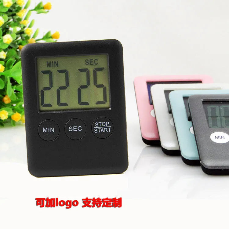 Black and white digital kitchen timer with magnetic back on a refrigerator.