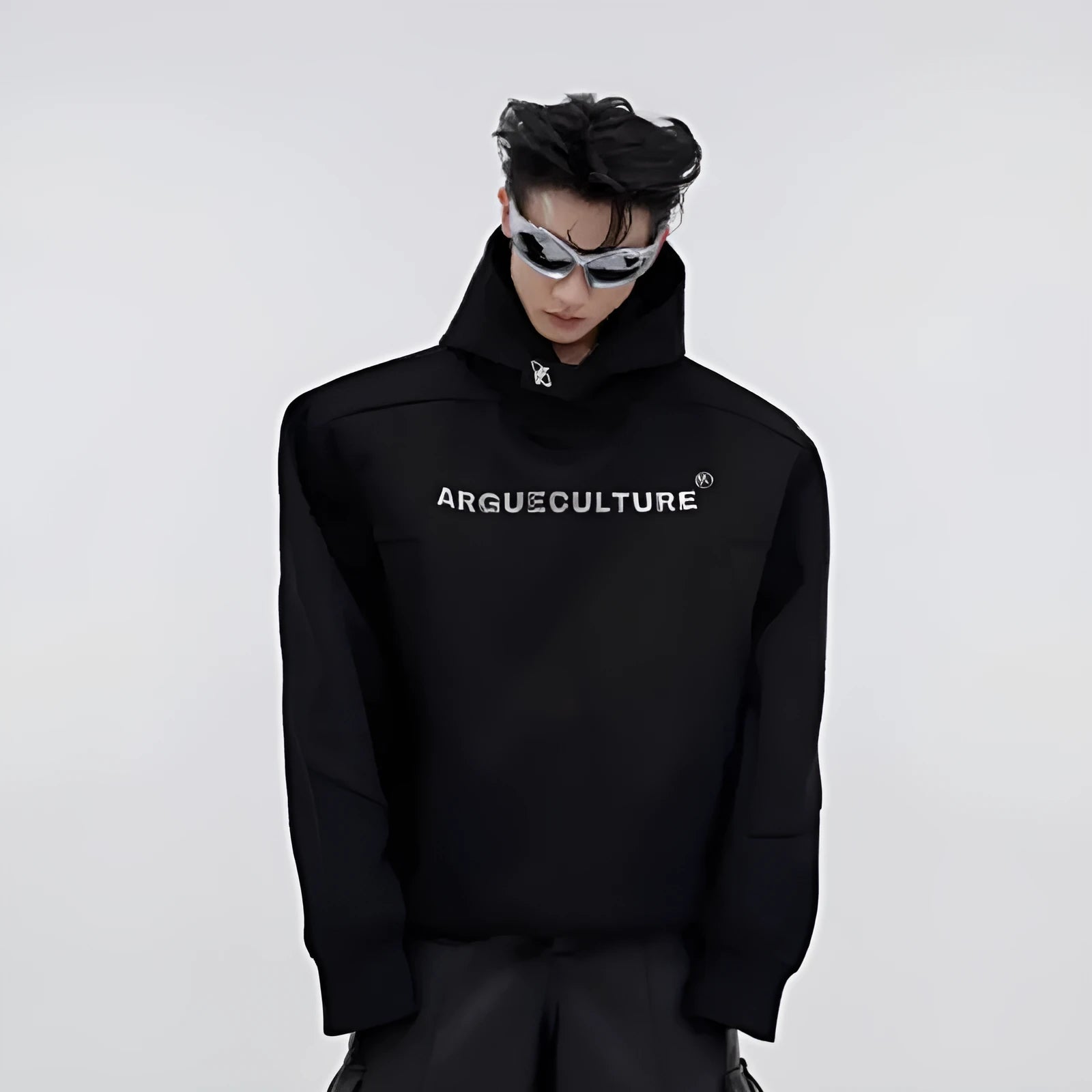 A man's loose black hooded sweater with heavy shoulder pads and a metallic three-dimensional printed design on the front.