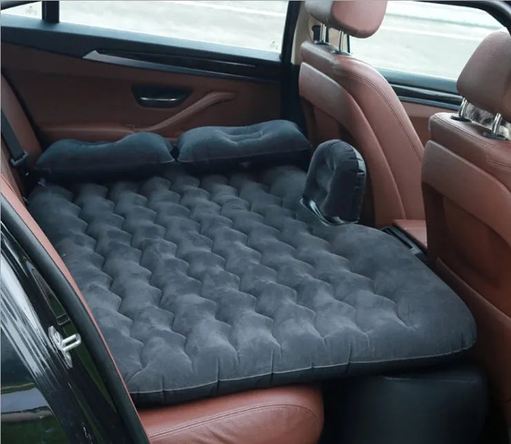 Inflatable car bed with flocked surface folded beside storage bag and two pillows