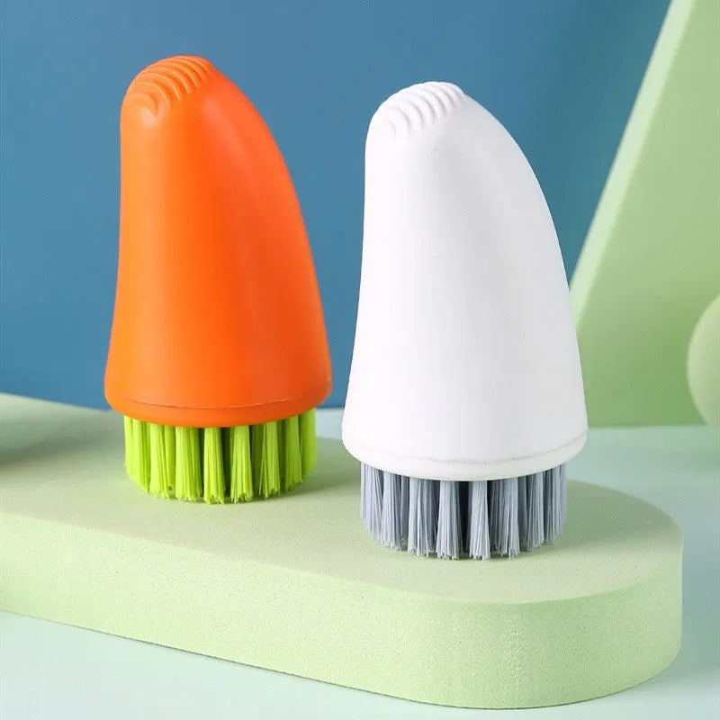 Orange and white carrot-shaped nylon kitchen cleaning brush with radish pattern on a wooden surface.