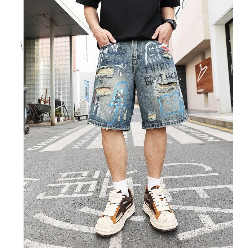 Blue ripped men's denim shorts with graffiti design, showing straight leg and zipper fly.