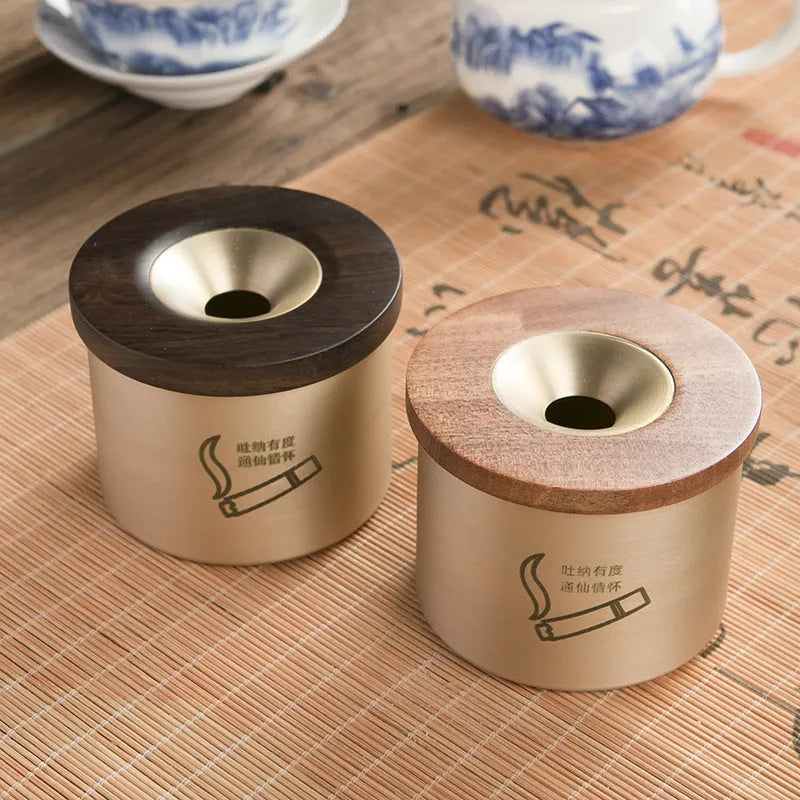 Retro-style solid copper ashtray with a wooden lid featuring a centre hole, shown in brass and black wood or brass and red wood.