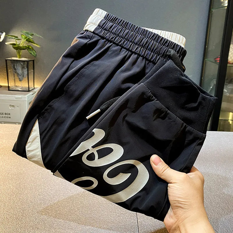 Men's black ice silk cropped ankle banded trousers on hanger showing thin fabric and banded ankle detail