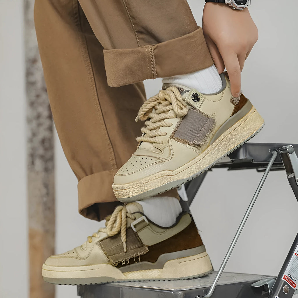 Beige low-top skateboard shoes with vintage patch detail and round toe on a rubber sole.