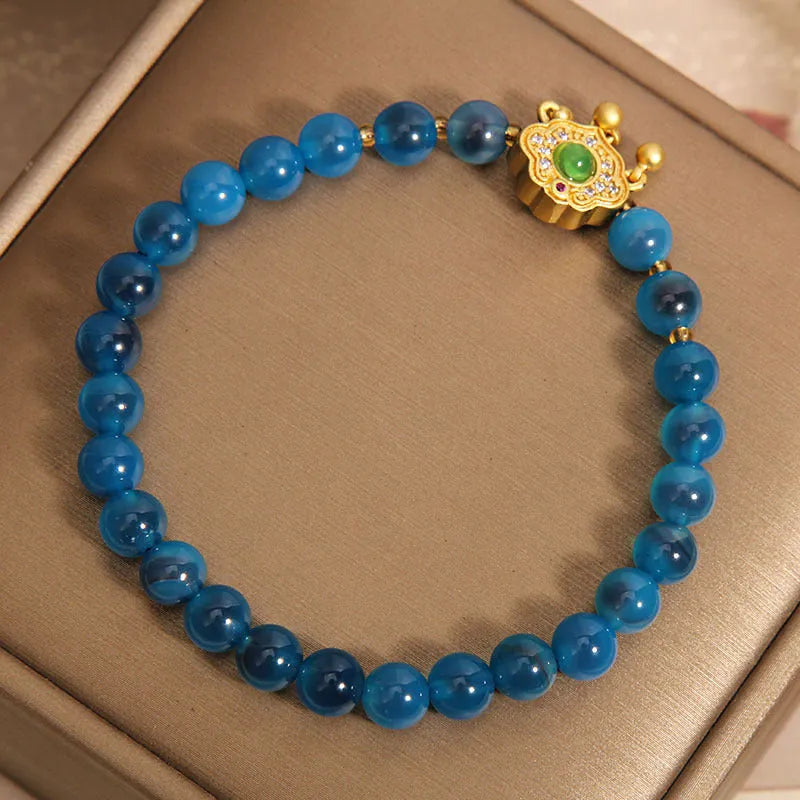 Close-up of a women's blue sugar heart agate safety lock pendant bracelet with crystal links and rhinestone detailing.
