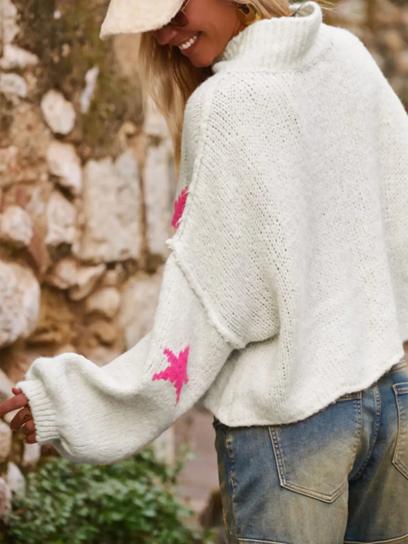 White women's loose turtleneck sweater with a large black five-pointed star pattern on the front.