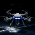 Plastic quadrocopter drone with GPS, remote controller, spare blades, and landing gear on grey background