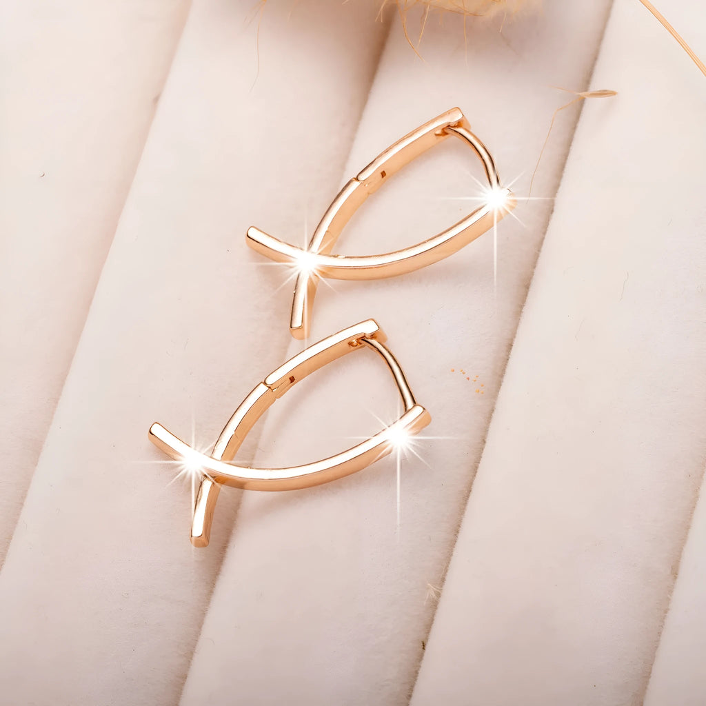Rose gold cross shaped earrings with copper construction on display card