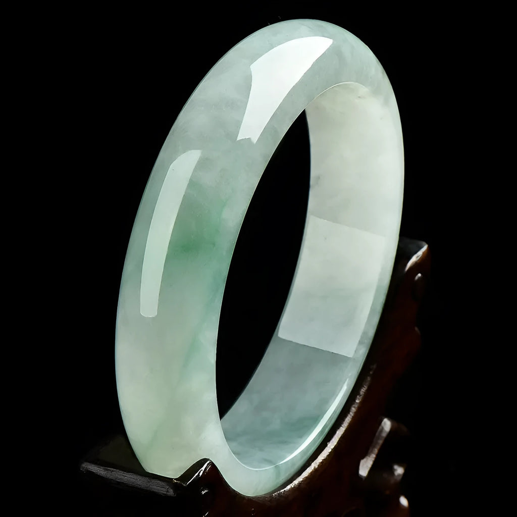 Natural light green jade bracelet with a metal clasp, shown on a wrist.