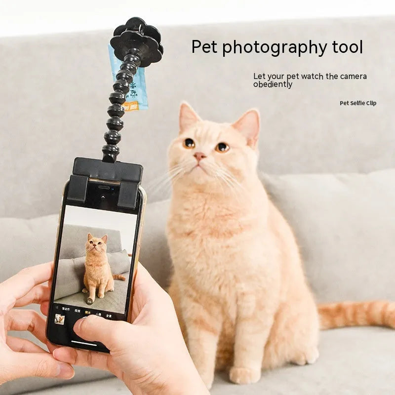 Black plastic pet photography clip holding a phone, with a rotating arm to grip dog or cat treats for photos.