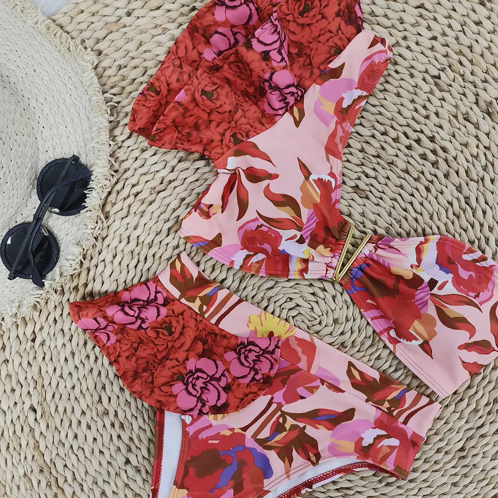 Pink one-shoulder ruffled swimsuit with red floral print and high-waist bikini bottoms