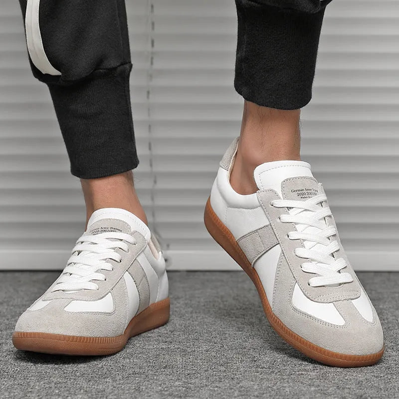 White low-top retro sneakers with mesh lining and rubber soles on a solid background