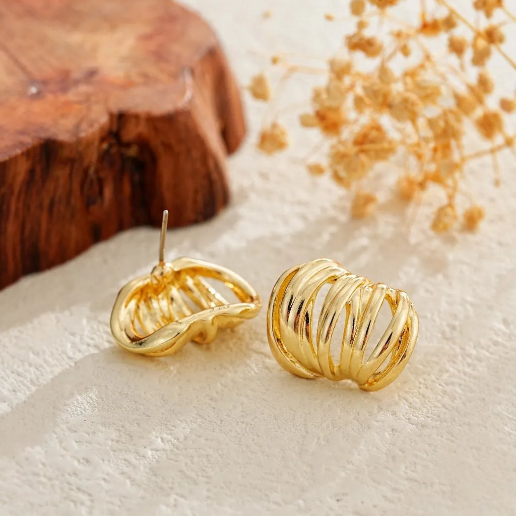 Gold metal ear loops with niche design and metal earrings on white background