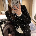 Women's grey dot pattern knitted cardigan with crocheted flower detail on a mannequin.