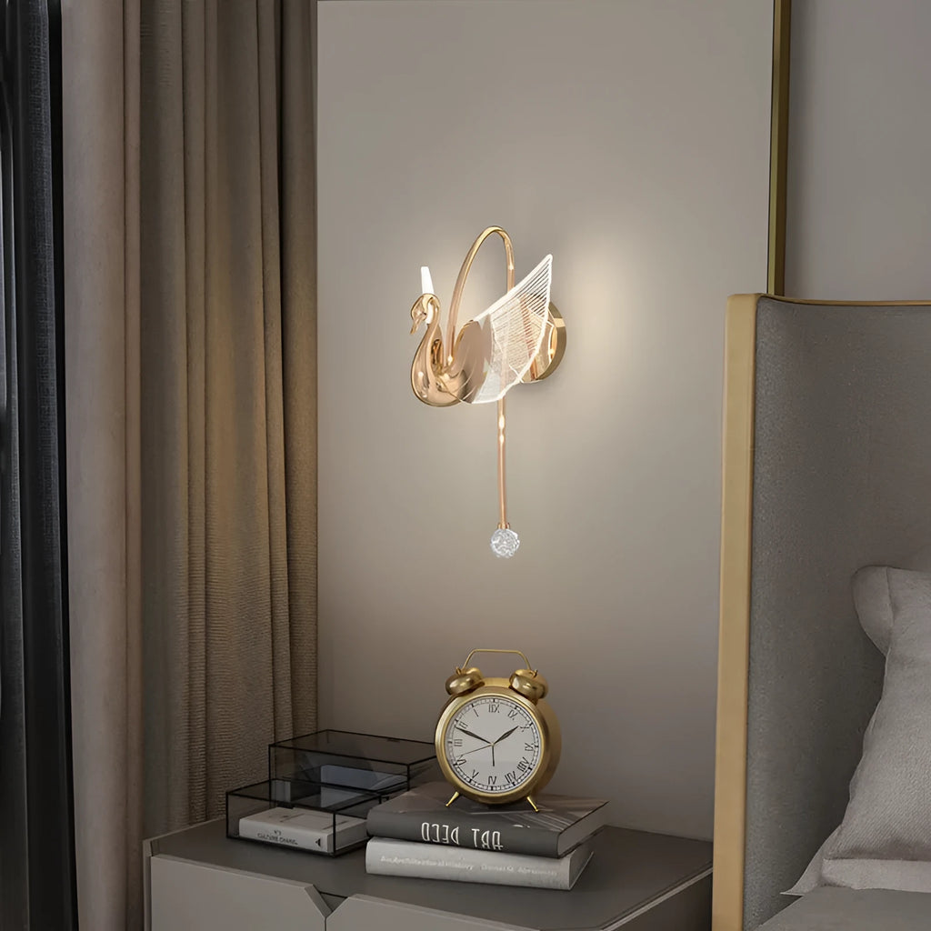 Gold swan-shaped modern minimalist wall lamp with acrylic shade on a wall.