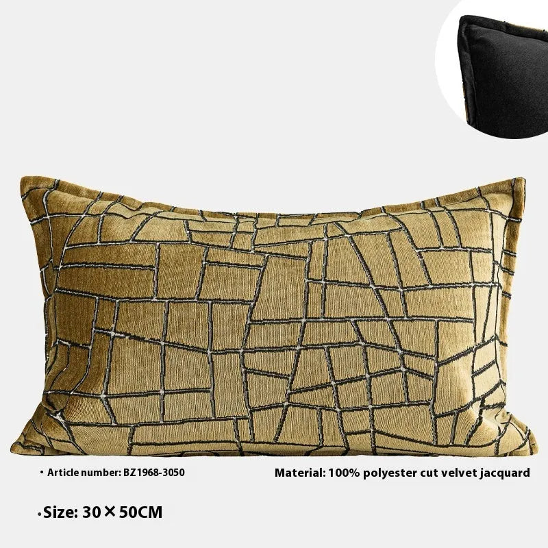 Gold geometric abstract patterned square cushion on a grey sofa.