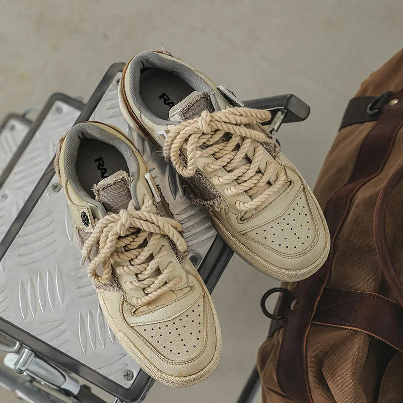 Beige low-top skateboard shoes with vintage patch detail and round toe on a rubber sole.