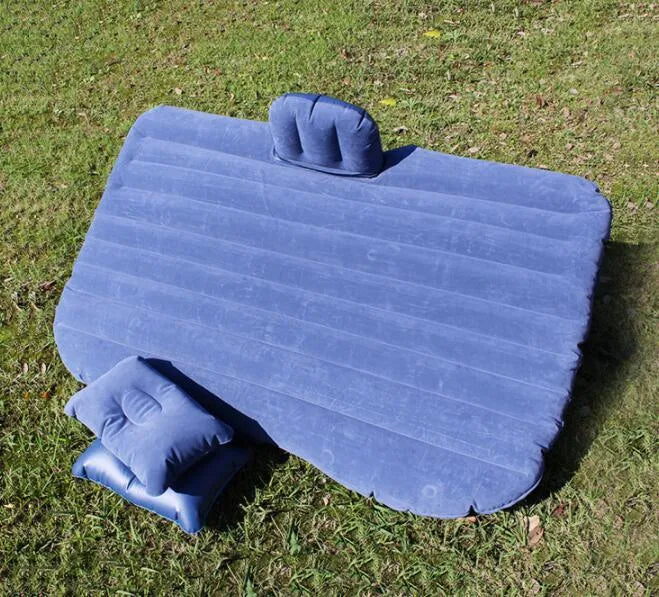 Inflatable car bed with flocked surface folded beside storage bag and two pillows