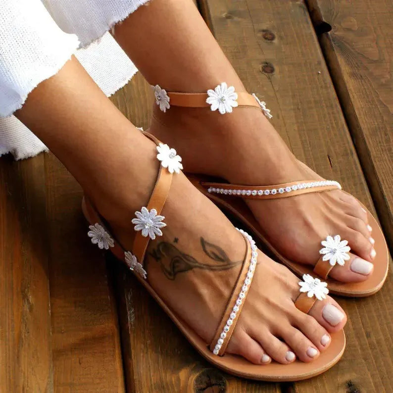 Brown women's Roman sandals with herringbone toe design and flower elements on flat rubber sole