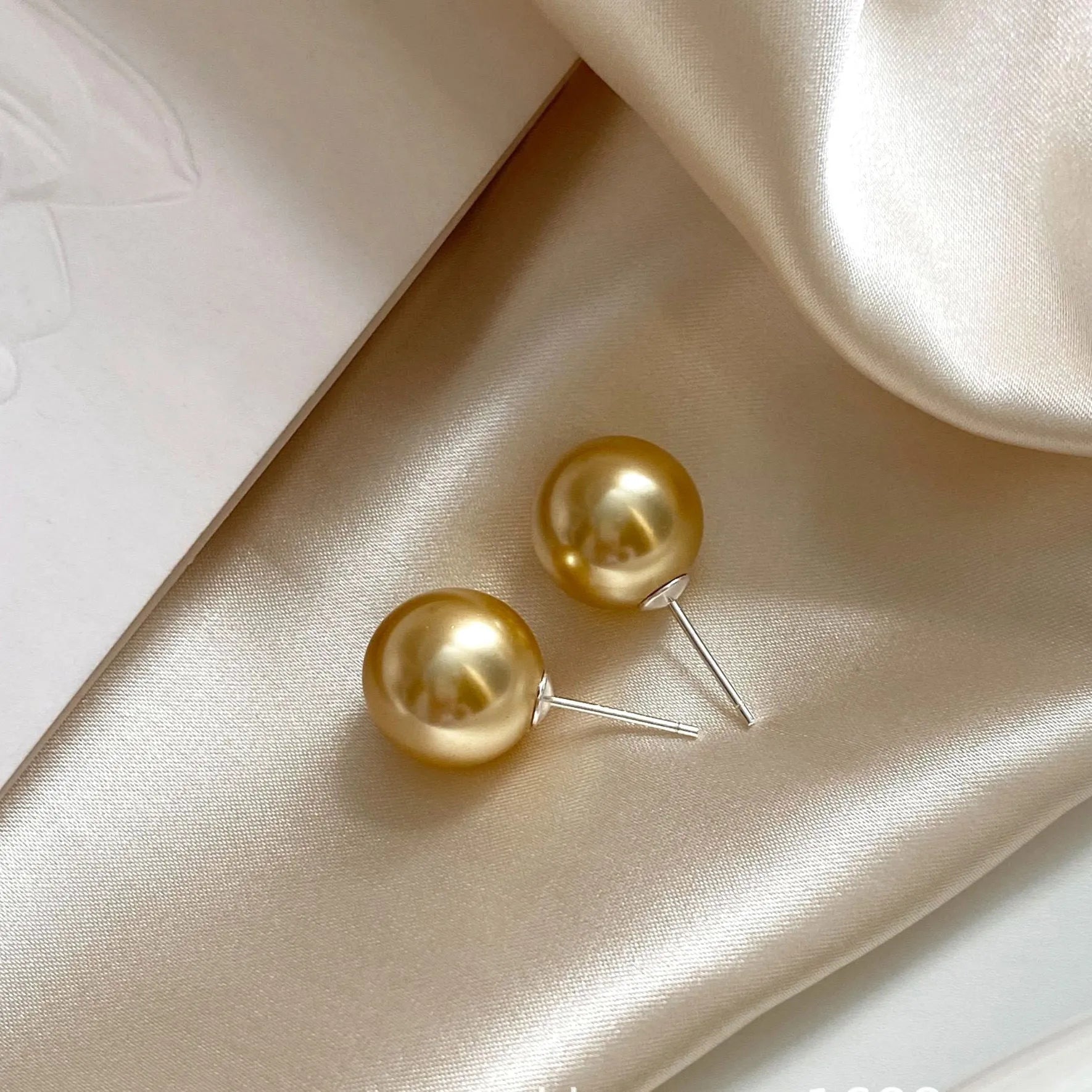 Large geometric pearl stud earrings for women in silver, showing eight-point star detail on setting.