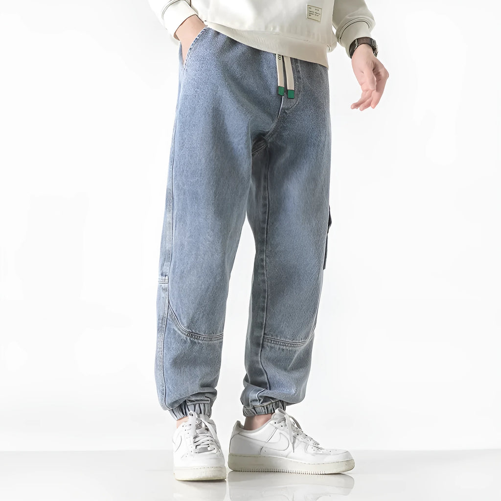 Men's loose-fit tapered cotton trousers in grey showing mid-waist design and tapered leg silhouette