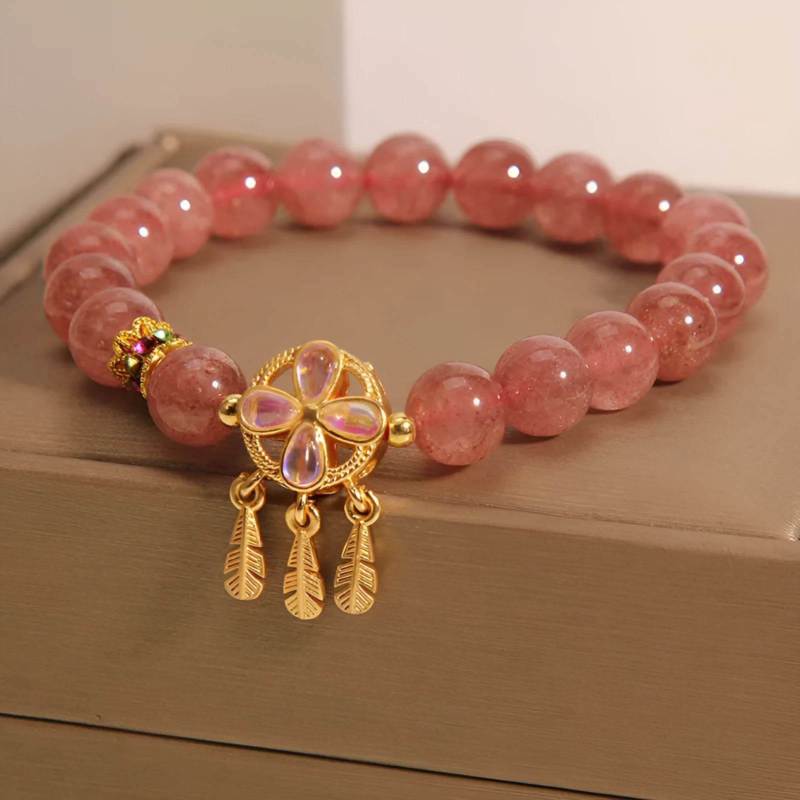 Women's strawberry quartz crystal bracelet with a four leaf dream catcher ball pendant.