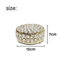French gold iron jewellery box with a clear crystal glass lid on a wooden surface.