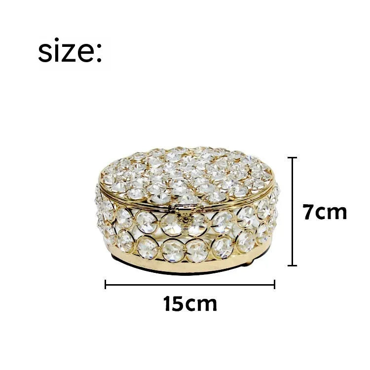 French gold iron jewellery box with a clear crystal glass lid on a wooden surface.