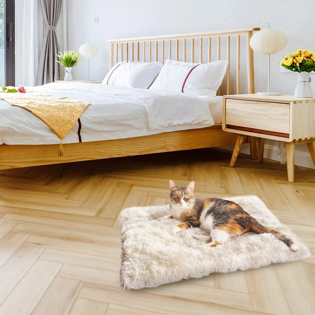 Grey plush pet blanket and bed with raised sides and a black non-slip bottom, shown on a wooden floor.