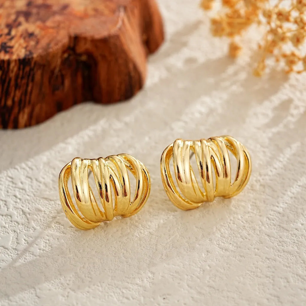 Gold metal ear loops with niche design and metal earrings on white background