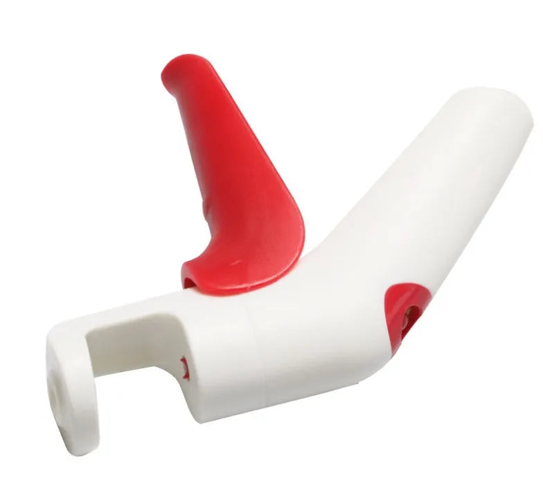 Red and black manual cherry pitter tool with detachable stone catcher on a kitchen worktop.