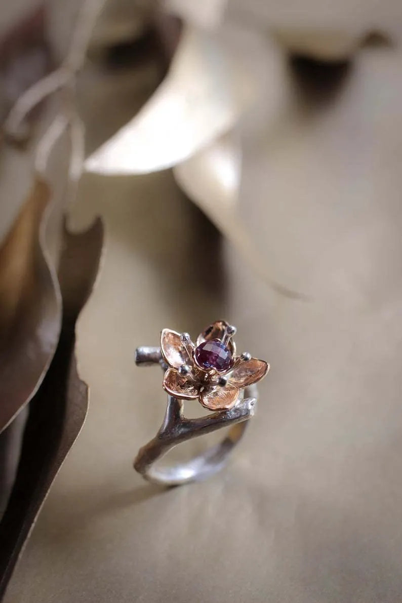 Silver two-tone women's ring with geometric shape and floral detailing on a hand.