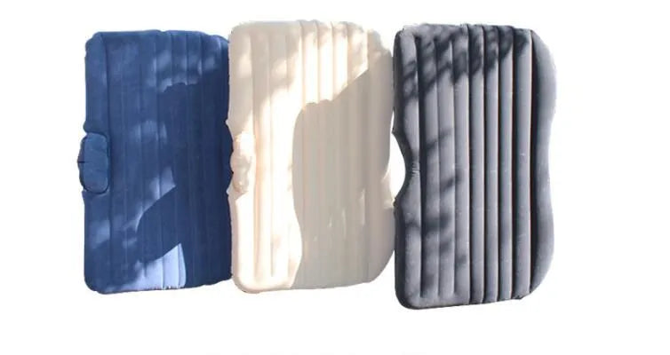 Inflatable car bed with flocked surface folded beside storage bag and two pillows