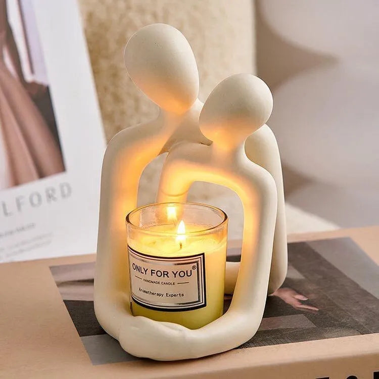Modern minimalist resin statue of a couple in milky white or gold colour on a wooden surface.
