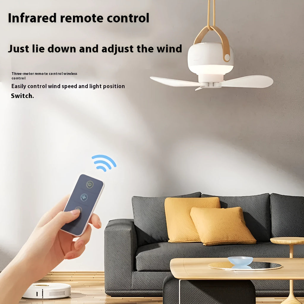 Small white rechargeable ceiling fan with fan blades and night light, hanging from a metal wire bracket for camping