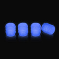 Luminous rubber tyre valve caps in light green, blue, red, yellow, and pink colours on a wheel valve.