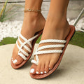 Women's white woven clip-toe flat sandals on a rubber sole, shown from a side angle.