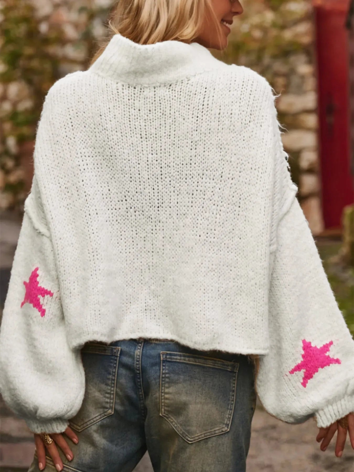White women's loose turtleneck sweater with a large black five-pointed star pattern on the front.