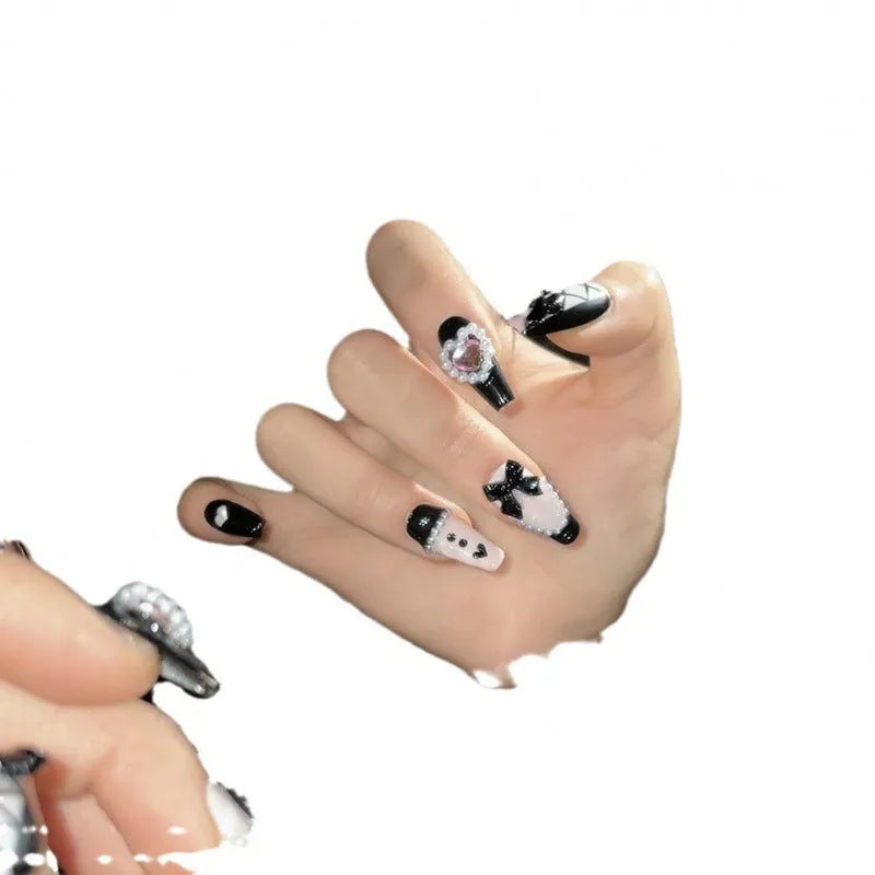 Handmade black and pink heart design artificial nails with bow, Xingx pattern, and cat's eye finish.