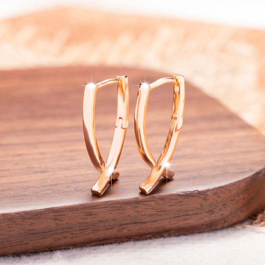 Rose gold cross shaped earrings with copper construction on display card