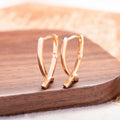 Rose gold cross shaped earrings with copper construction on display card