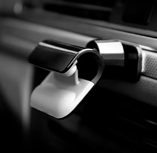 Black universal gravity car phone holder mounted on a dashboard, showing 360-degree rotation.