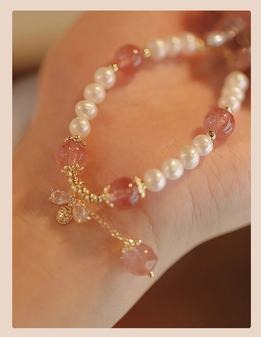 Close-up of a women's hand-strung strawberry quartz crystal bracelet with a decorative bow.