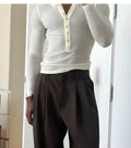 Man wearing a cream coloured ribbed knit long-sleeve henley top with a crew neck.