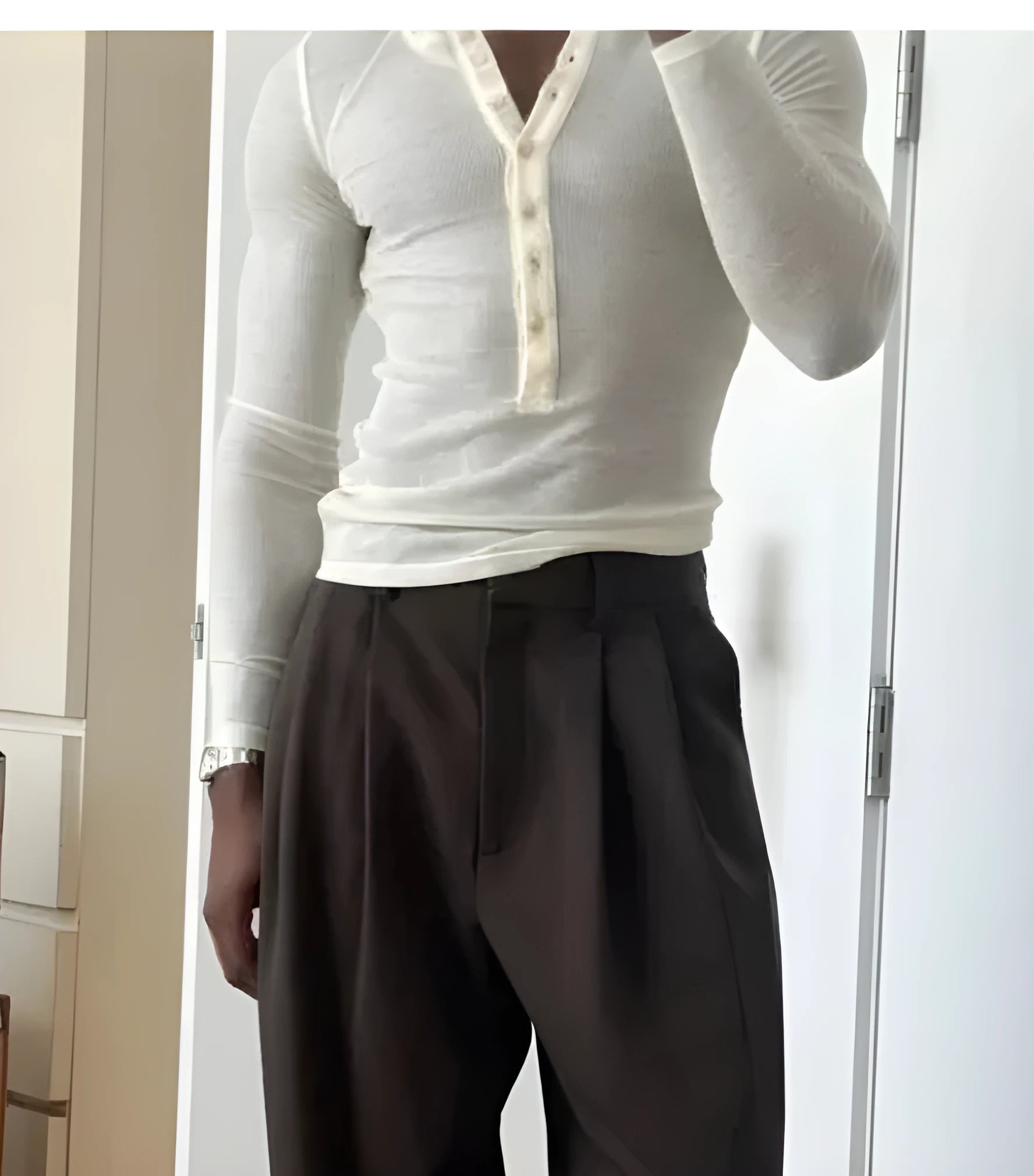Man wearing a cream coloured ribbed knit long-sleeve henley top with a crew neck.