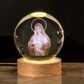 White crystal ball ornament on wooden base with religious symbols and warm light illumination