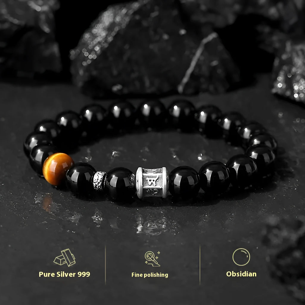 Men's black obsidian and silver bracelet with a 10mm prayer wheel charm on a dark background.