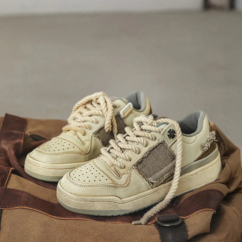 Beige low-top skateboard shoes with vintage patch detail and round toe on a rubber sole.